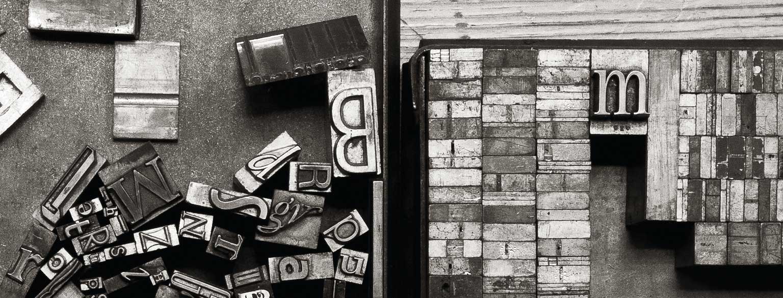 Masthead Graphic: On the left, a variety of metal type sorts for handset letterpress printing in a resorting tray; on the right, a tray of various metal quads.